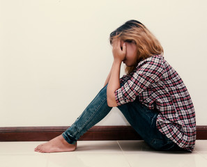 young hipster woman, sad, long-haired  sitting hugging legs.