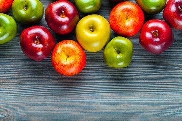 Ripe red green and yellow apples on wooden board background