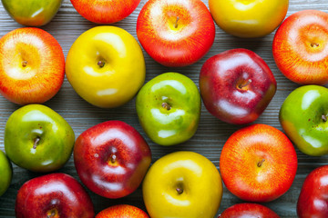 Ripe red green and yellow apples on wooden board background