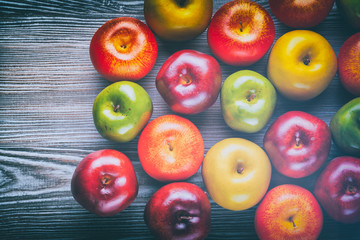 Ripe red green and yellow apples on wooden board background