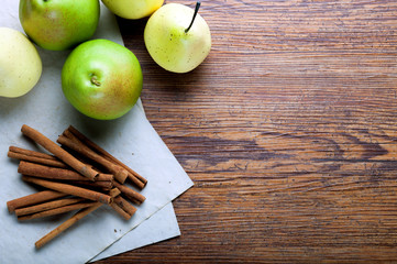 Ripe pears and cinnamon sticks on rustic wooden board, copy space