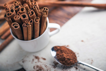 Cinnamon sticks and powder on rustic wooden board top view