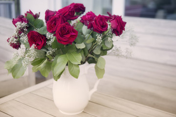 vase with red roses on a wooden table