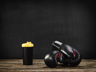 Pair of boxing gloves on a vintage wooden desk with chalkboard background. Concept image, the idea of brutal competition.