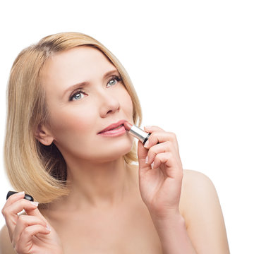 Beautiful middle aged woman applying lipstick