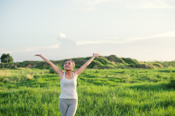 Fototapeta na wymiar Happy beautiful woman with stretched arms in meadows with fresh