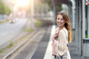 Fototapeta premium Attraktive Frau wartet an einer Haltestelle
