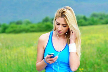 Young woman listening to music while working out outdoors in early morning