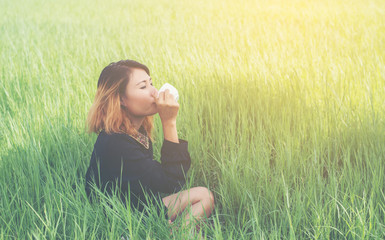 Young hipster woman sitting on green grass drinking hot coffee a