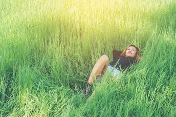 beautiful young woman lying down on green grass enjoy life and h