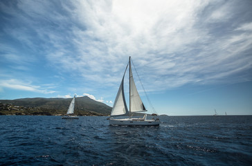 Fototapeta premium Beautiful yacht sailing on the sea near the island coast.