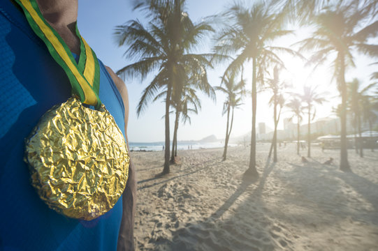 Gold medal athlete standing in front of palm trees in Leme, at Copacabana Beach in Rio de Janeiro, Brazil