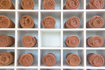 rolled up brown spa towels on wooden cabinet