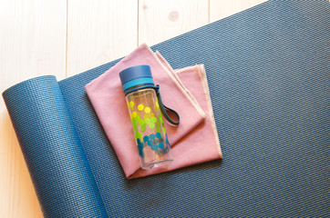 Water bottle, sport towel on dark blue mat.Concept for yoga, pilates or fitness.