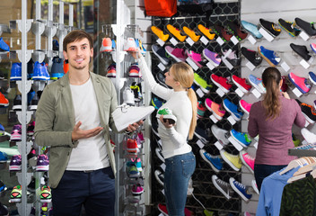 three young persons showing an assortment of the shoes in the st