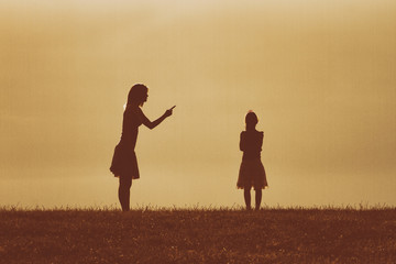 Silhouette of a angry mother scolding her daughter.