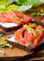 Sandwich with cereals black bread and salmon on wooden board background