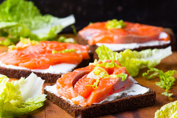 Sandwich with cereals black bread and salmon on wooden board background