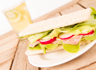 Crispbread sandwich with headcheese, cheese, radish and lettuce and a glass of lemonade