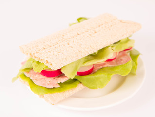 Crispbread sandwich with headcheese, cheese, radish and lettuce on a white background