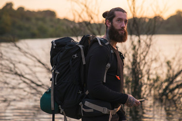 Backpacker with cellphone near lake
