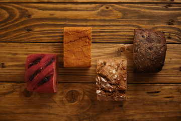 Pieces of mixed homemade breads presented in different levels on wooden table as samples for sale: , sweet potato, sea salt, rye and beetroot Top view