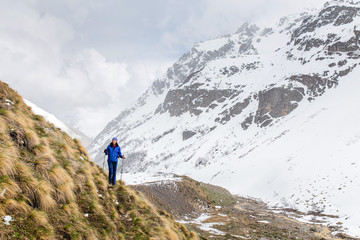 tourist hiker walking in mountains near the snowfield and glacier. Offseason trekking concept