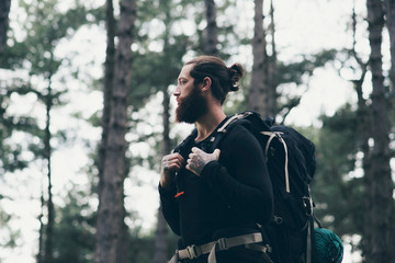 Obraz premium Bearded man with backpack trekking in forest