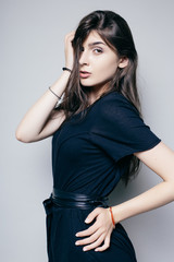 Fototapeta premium Young brunette lady in black dress posing on grey background