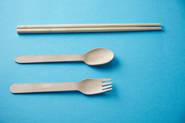 Mixed of kitchen utencils for takeaway: asian chopsticks, spoon or fork made from recycled paper or wood, eco friendly, top view presented top view on blue