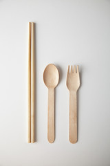 Kitchen utencils set for takeaway business: wooden recycling eco spoon, fork and chopsticks isolated on white top view