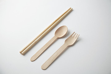 Kitchen utencils set for takeaway business: wooden recycling eco spoon, fork and chopsticks isolated on white side view
