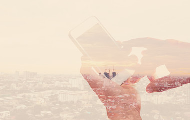 Double exposure hand using mobile phone and building in city bac