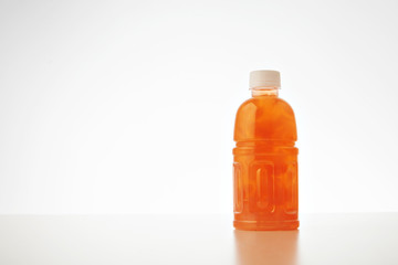 One takeaway bottle with drink from coconut cream and milk mixed with fruits and berries isolated on white Healthy refreshment sweet drink with peach bites inside.