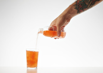 Hand pours from takeaway bottle drink from coconut cream and milk mixed with fruits and berries isolated on white Healthy refreshment sweet drink with watermelon bites inside.