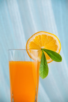 Fresh squeezed orange juice with sliced oranges and green leaf with sea on a background. Healthy drink in the morning.