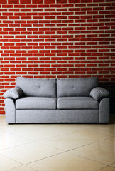 Grey sofa on a red brick wall background