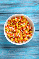 Halloween candy corns in bowl on blue wooden background