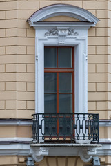 A window with an arch and balcony on the facade of the beige building. From the series window of Saint-Petersburg.