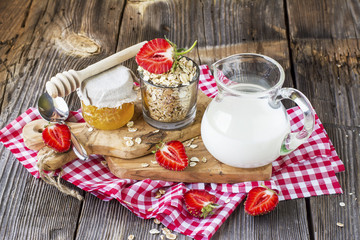 Oat flakes, milk, strawberries for breakfast on a gray wooden background