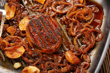 Grilled pork chop with onion on the pan on wooden background