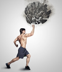 Shirtless athletick male kicking big grey rock. © Fxquadro