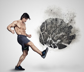 Shirtless athletick male kicking big grey rock. © Fxquadro