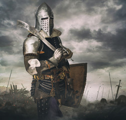 Knight in armour on battle rise under stormy sky.