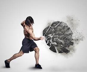 Shirtless athletick male kicking big grey rock. © Fxquadro