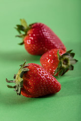 Three juicy strawberry on green background