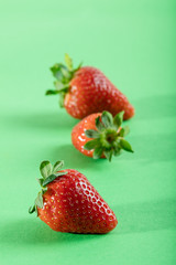 Three juicy strawberry on green background
