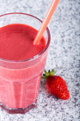 Glass with strawberry cocktail on granite board