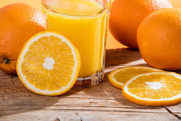 Fresh orange juice and oranges on wooden table