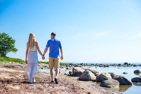 Back View Of Happy Couple In Love Walking On Summer Beach